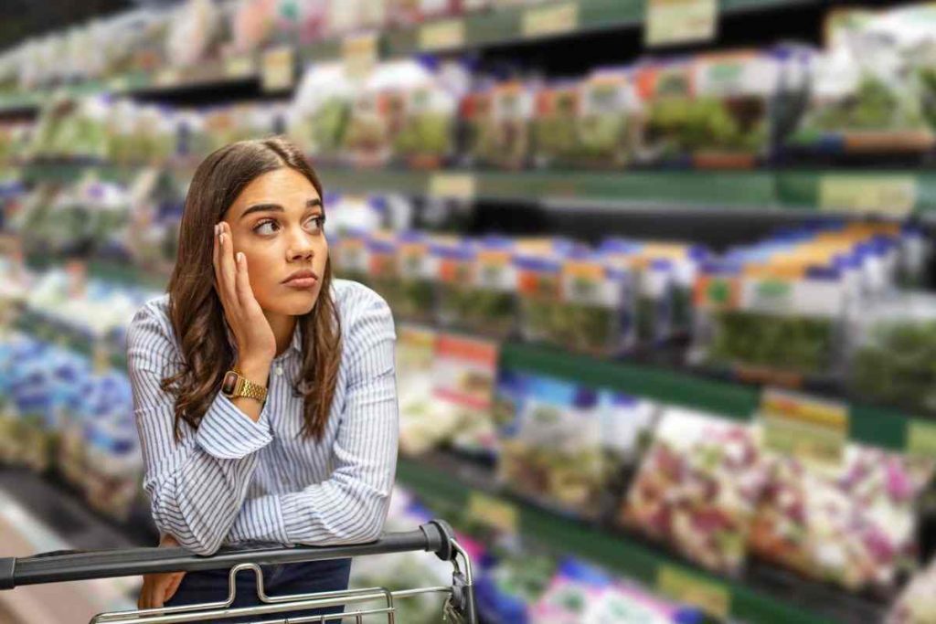 donna al supermercato appoggiata su un carrello