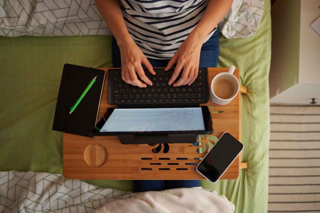 Persona lavora sul letto di casa al computer