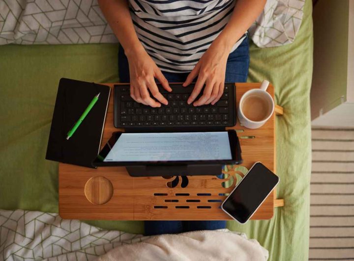 Persona lavora sul letto di casa al computer