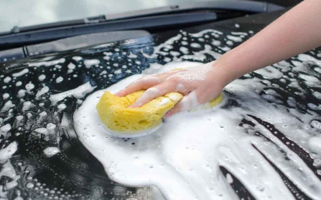 Uomo mette il sapone all'auto